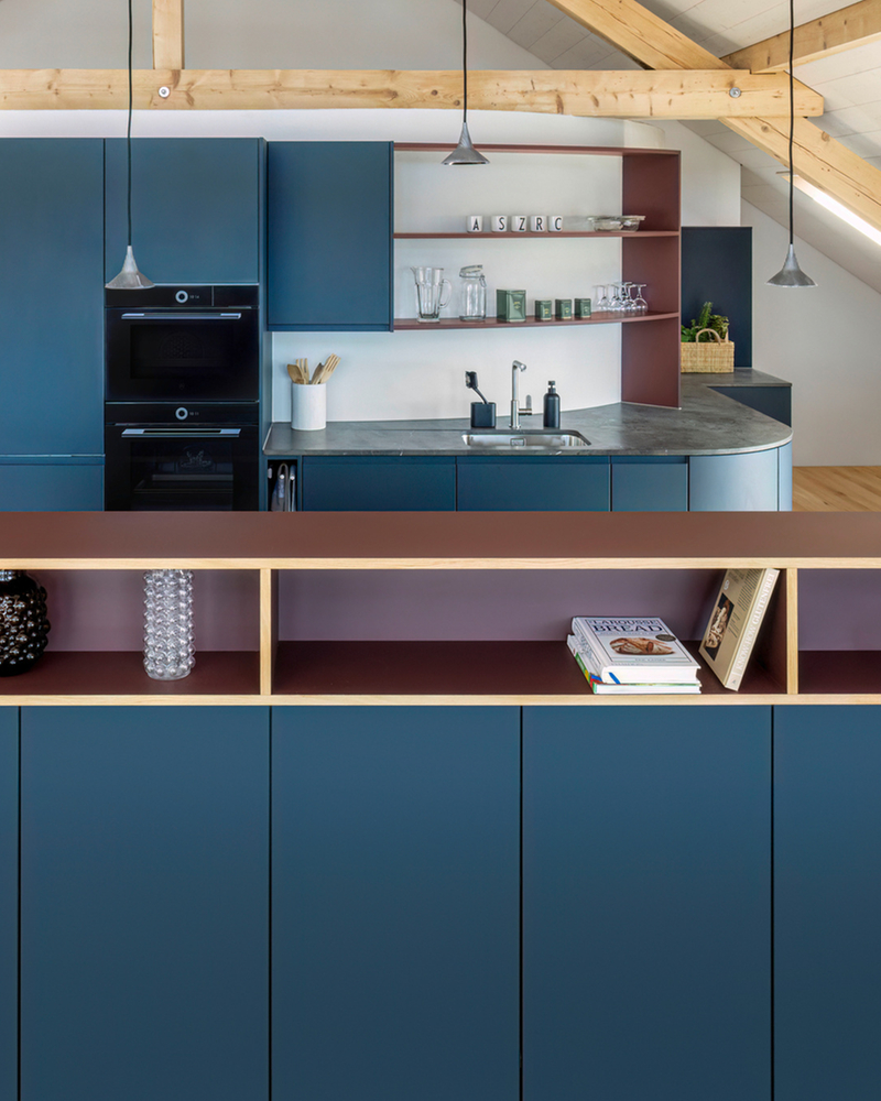 Modern kitchen with blue cabinets, wooden details and integrated appliances in an open space