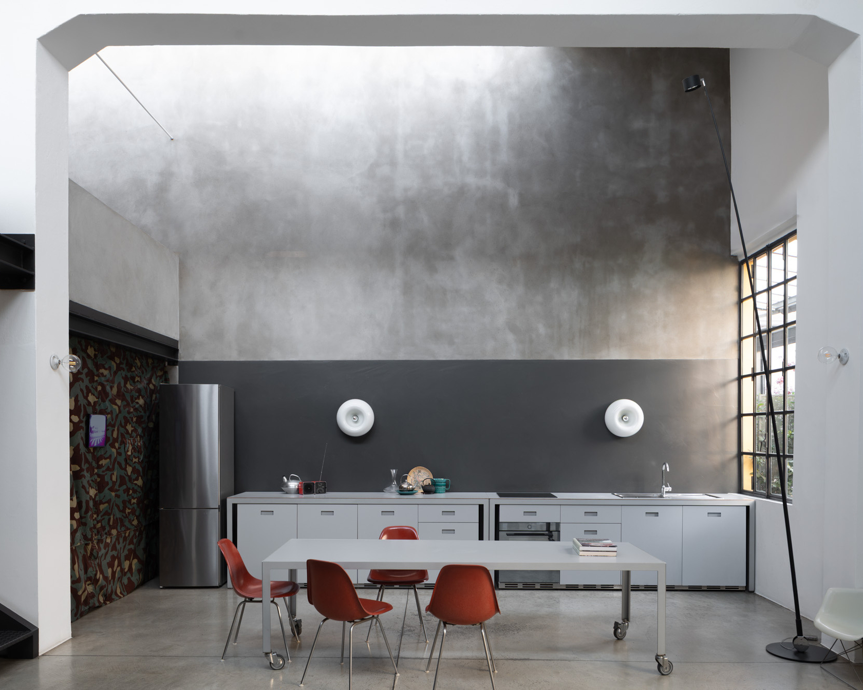 Moderne Küche mit minimalistischem Design, Edelstahl-Kühlschrank und stilvollen Möbeln in einem hellen Loft.