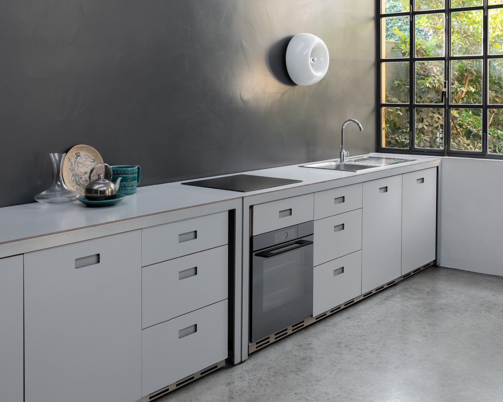 Moderne Küche mit Einbaugeräten, grauen Wänden und großen Fenstern