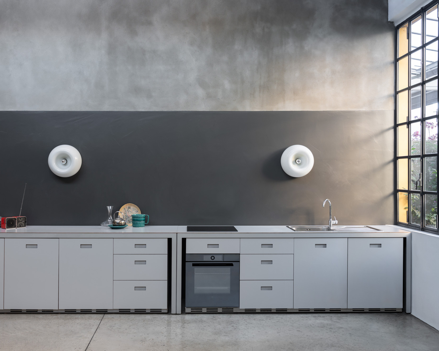 Moderne Küche mit grauen Fronten, Einbaugeräten wie Backofen, Kochfeld und Kühlschrank, minimalistisches Design.