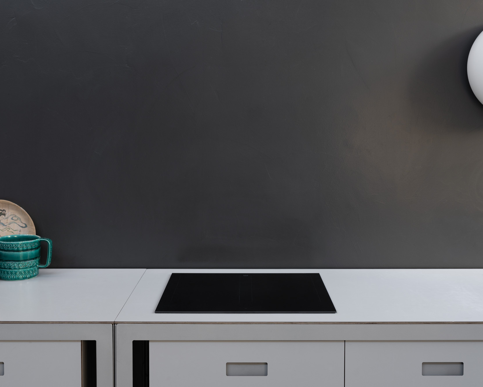 Modernes Kochfeld in einer minimalistischen Küche mit grauer Wand und stilvollen Details.