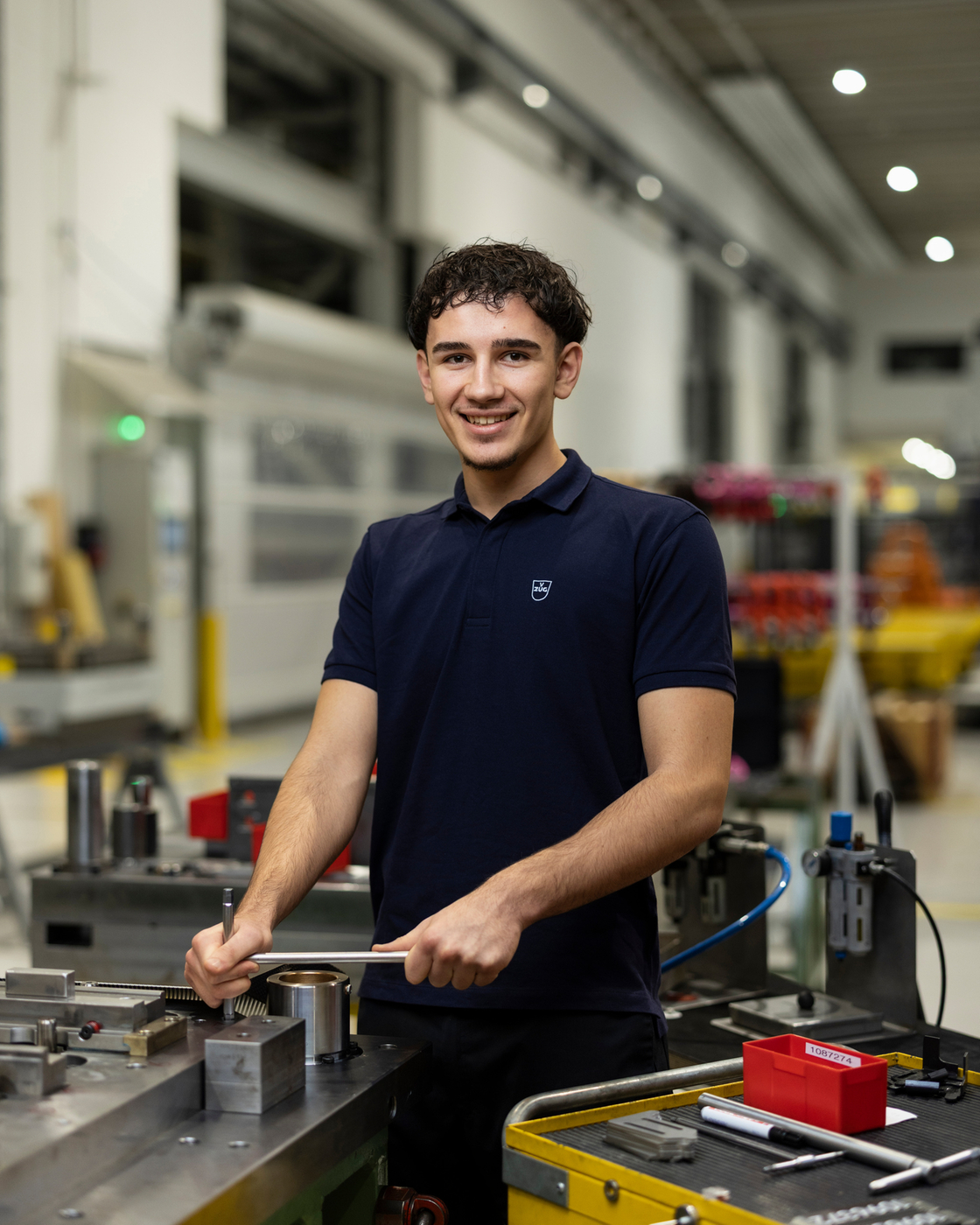 Mitarbeiter in einer Werkstatt mit Maschinen und Werkzeugen in einer Produktionshalle.