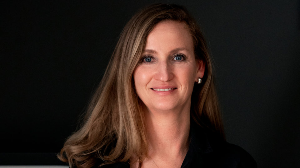 Person with brown hair in front of a dark background