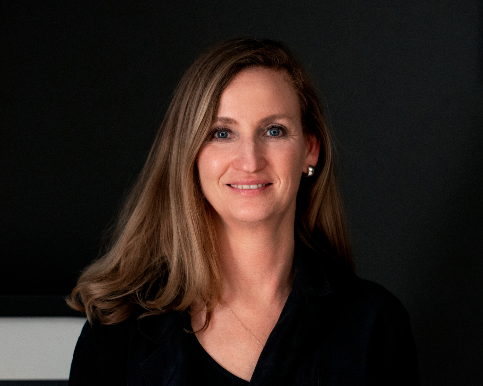Person with brown hair in front of a dark background