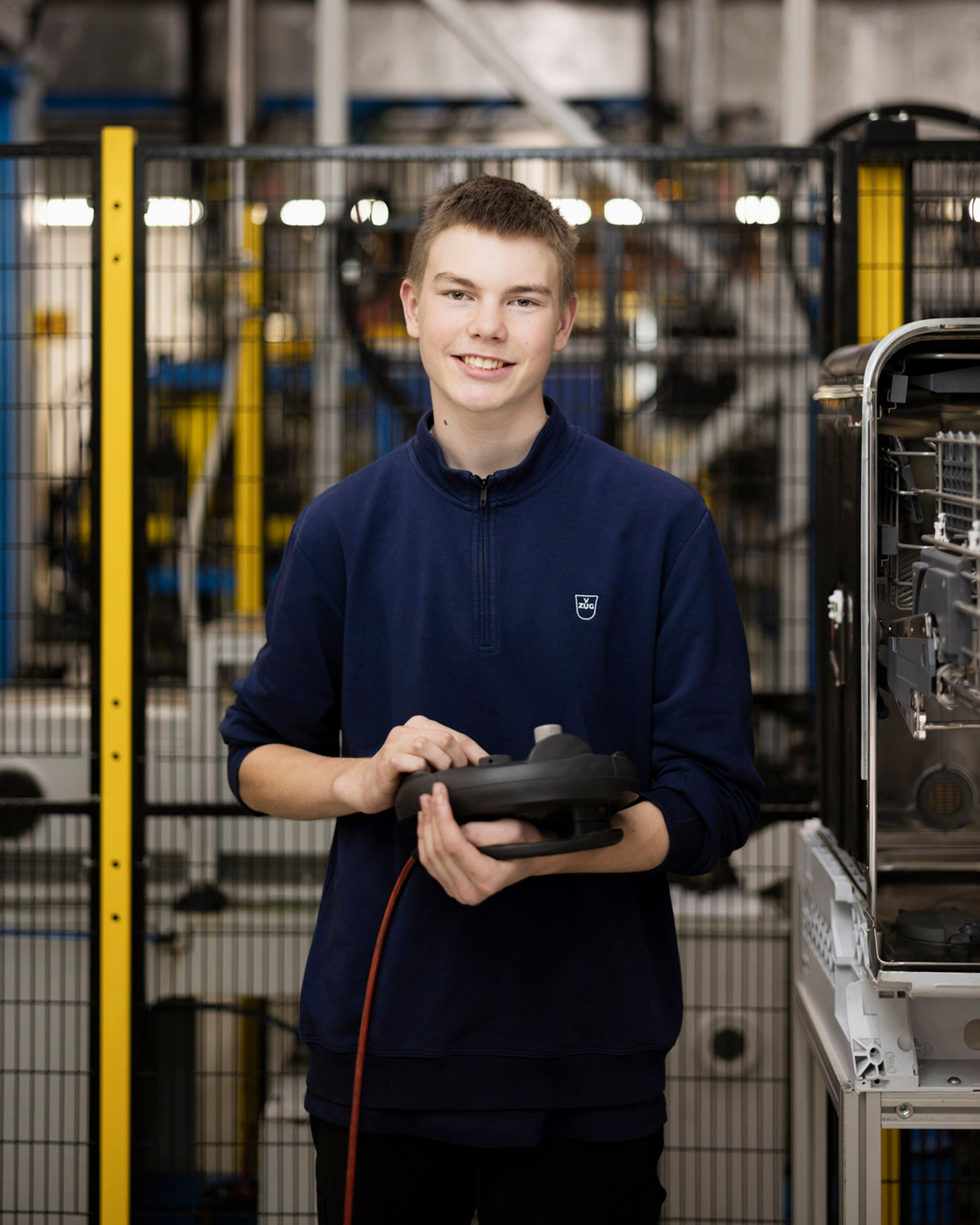 Dipendenti in un ambiente di produzione con un componente in mano, circondati da macchine e sistemi.