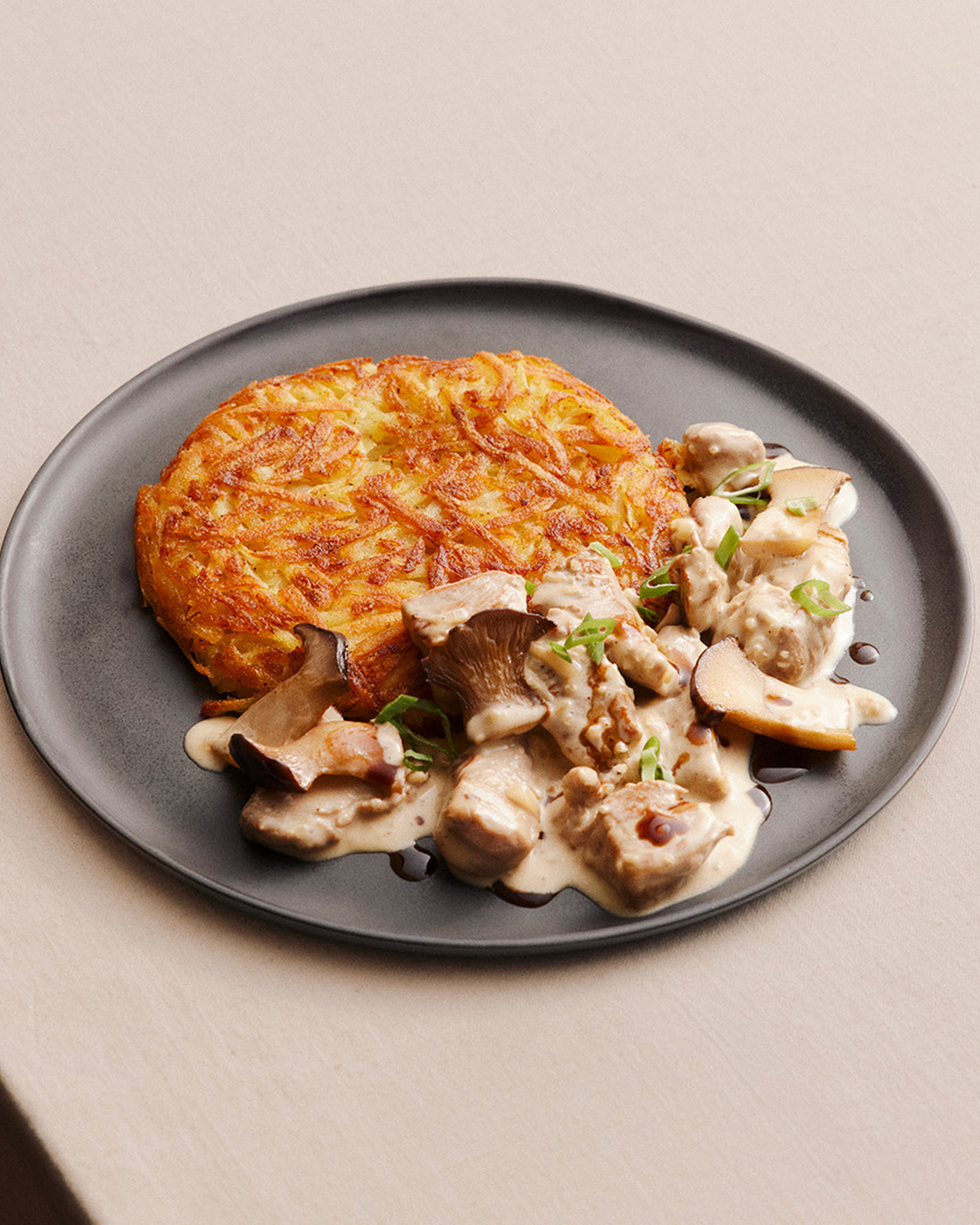 Knusprige Rösti mit cremiger Pilzrahmsauce auf einem Teller.