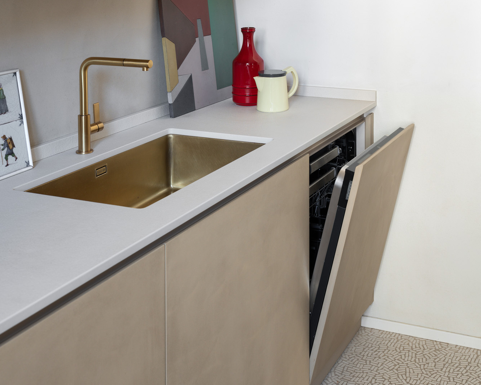 Open dishwasher in a modern kitchen with golden sink and elegant decoration.