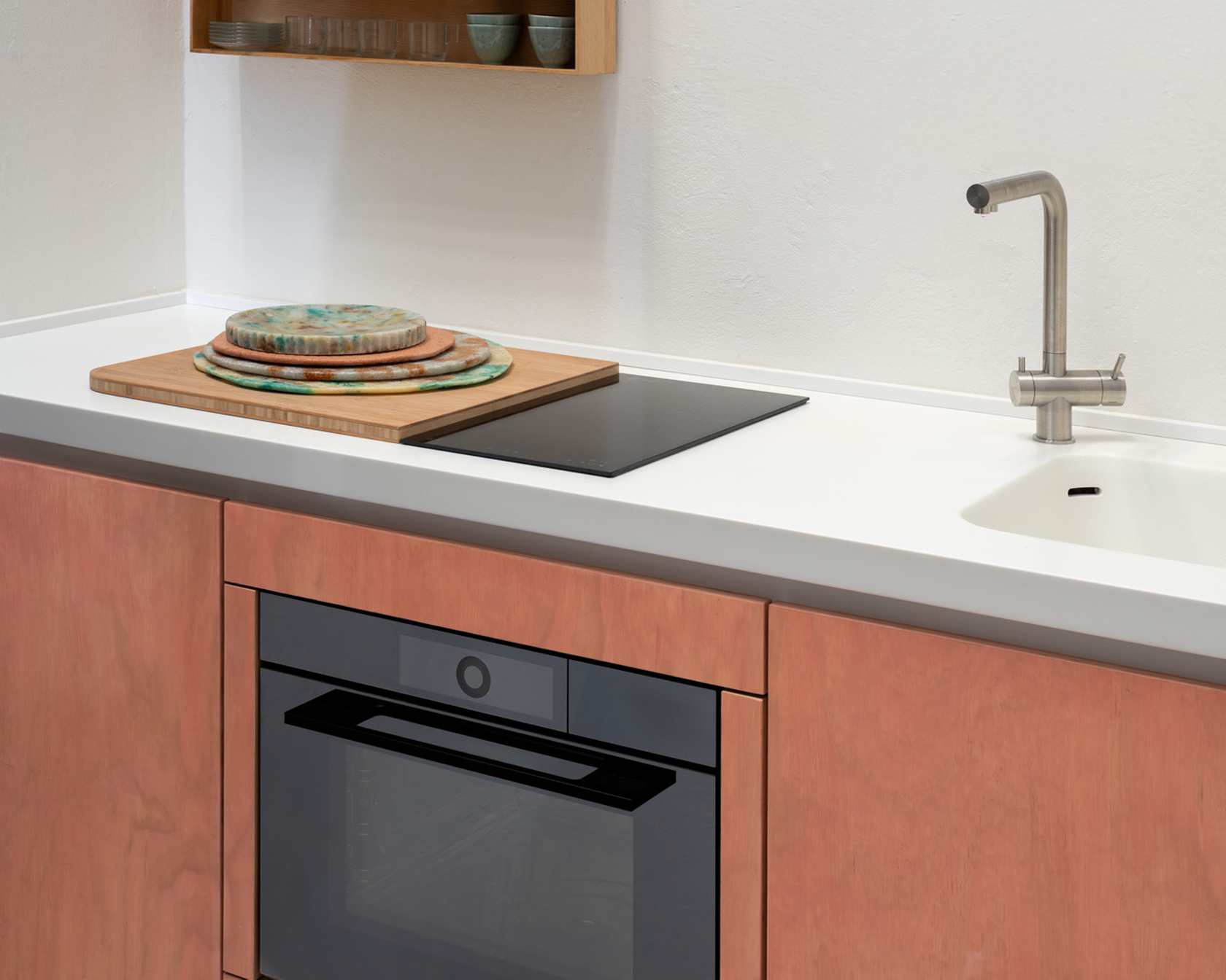 Modern kitchen with oven, hob and wooden cupboard.