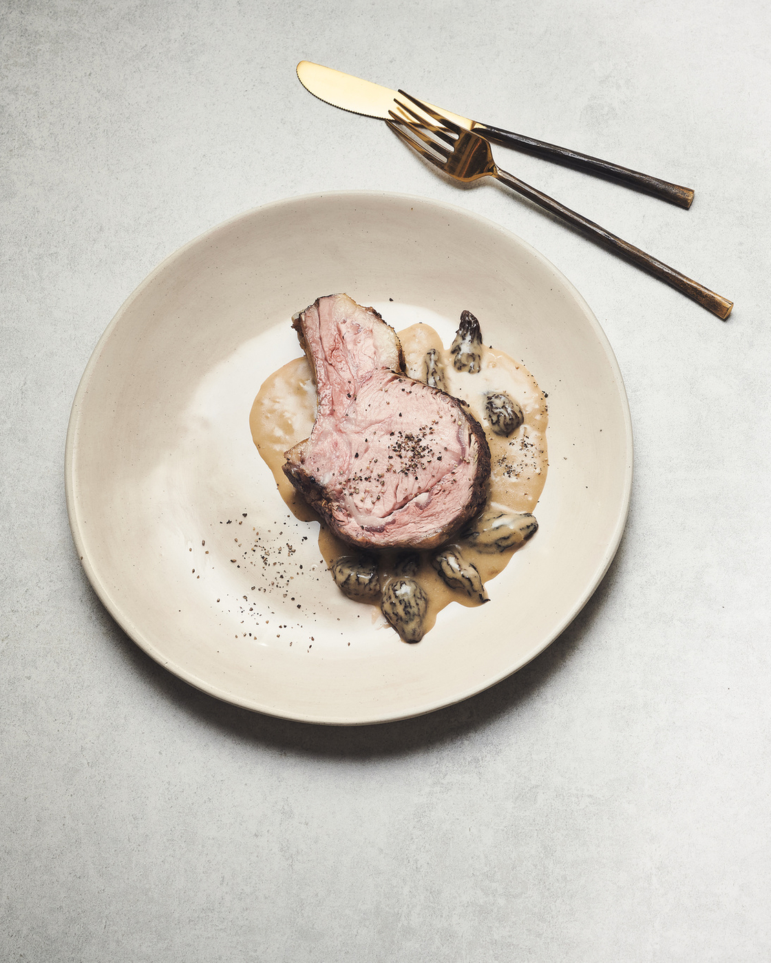 Dish on a plate with cutlery, presented in a minimalist style.