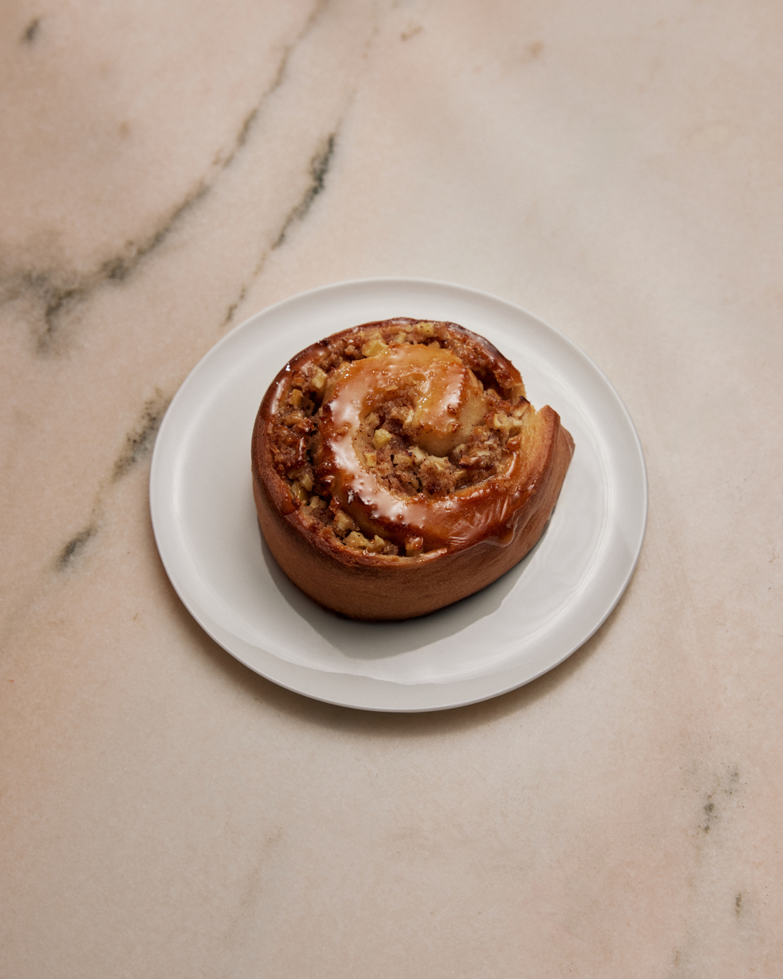 Cinnamon bun on a plate on a marble table