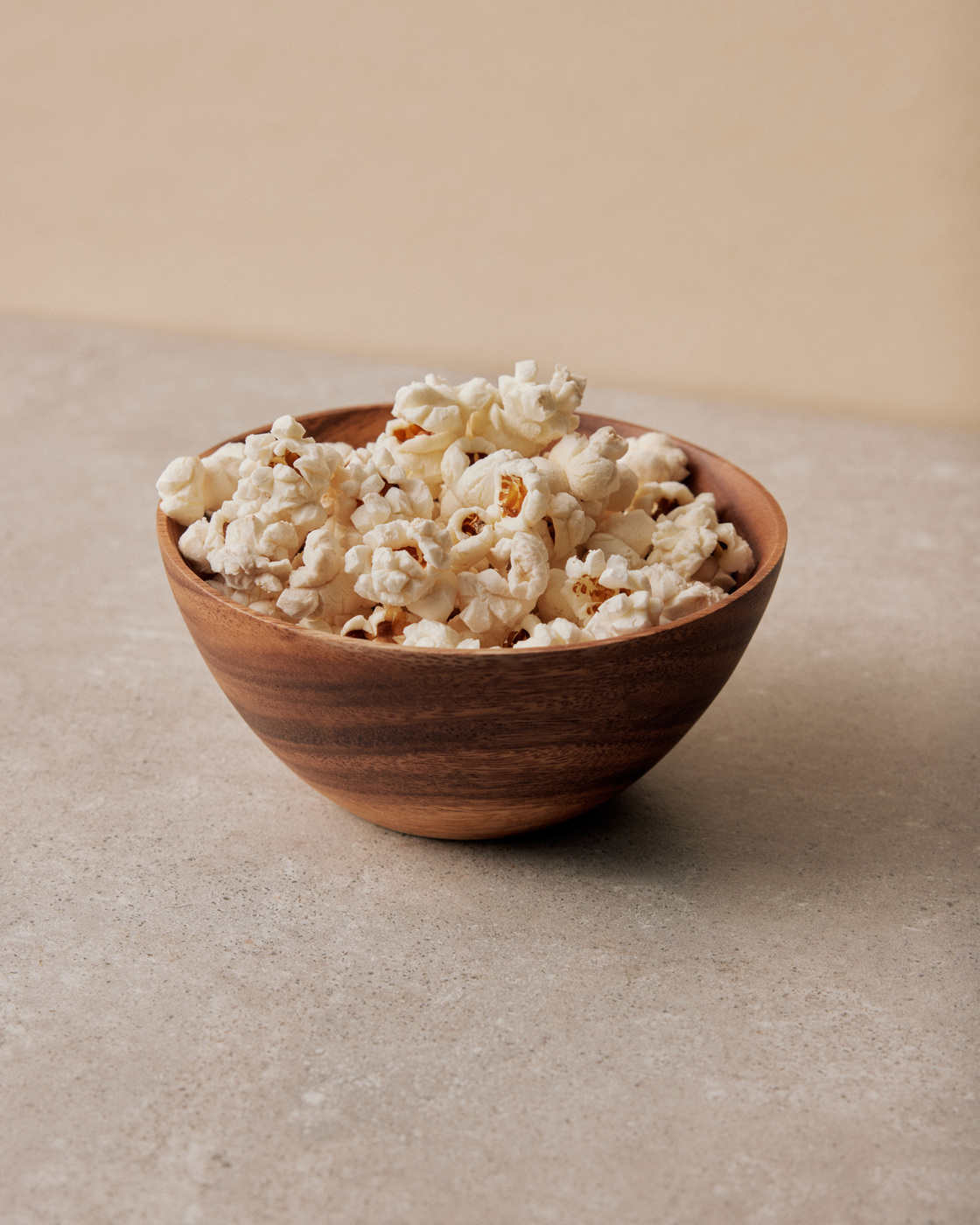 Ciotola di legno con popcorn su una superficie di pietra