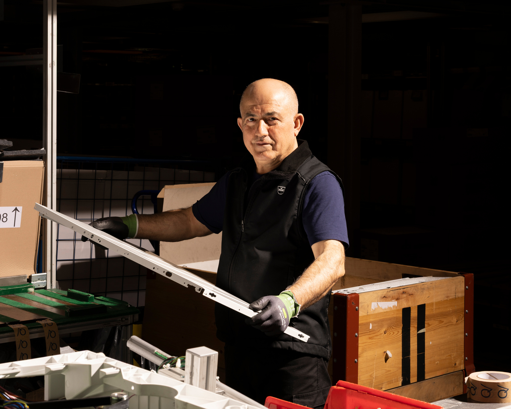 Employees assembling a component in a production environment with tools and materials.