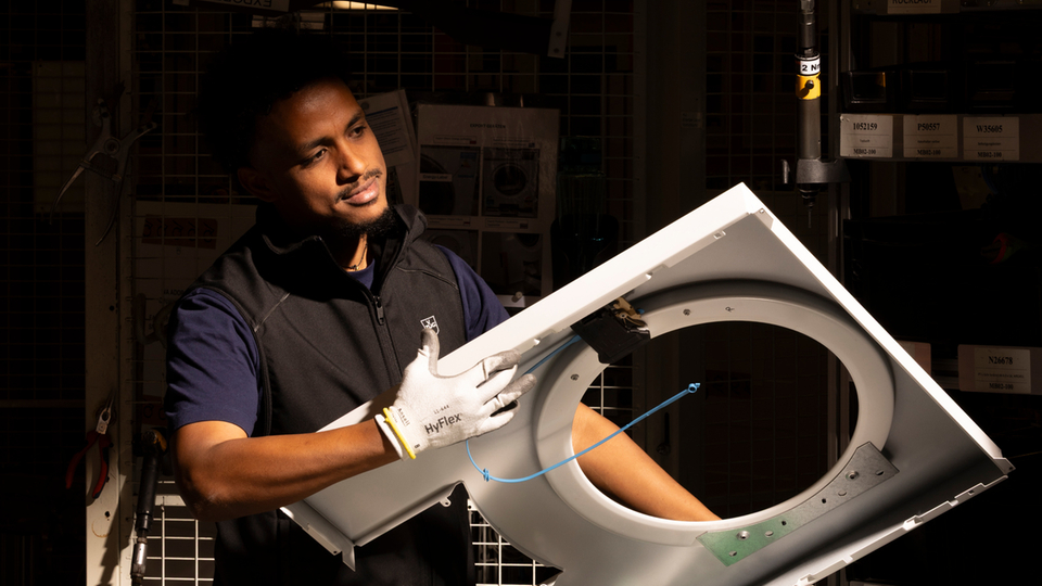 Installation of an extractor fan in a production facility with a worker in the background.