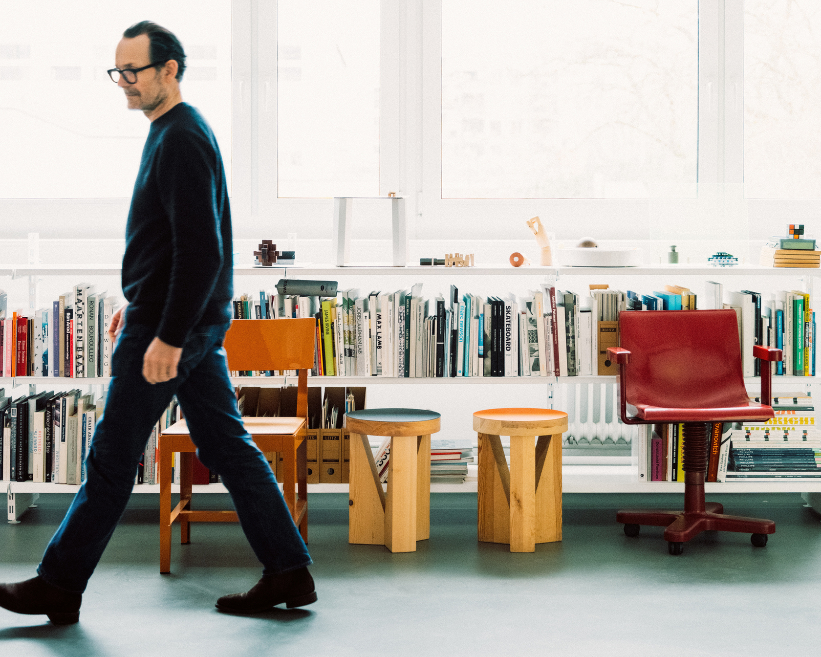 Mann in einem modernen Studio mit Bücherregal und Stühlen
