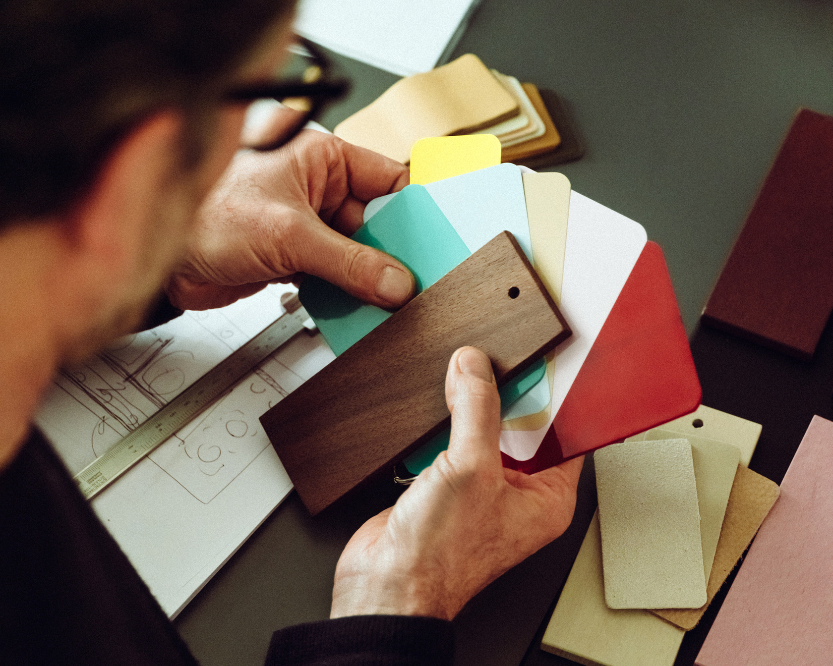 Materialproben und Farbmuster werden von einer Person begutachtet, um Designentscheidungen zu treffen.