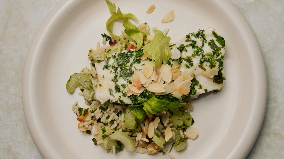 Fish dish with rice, herbs and slivered almonds on a plate, perfect for the kitchen or cooking inspiration.