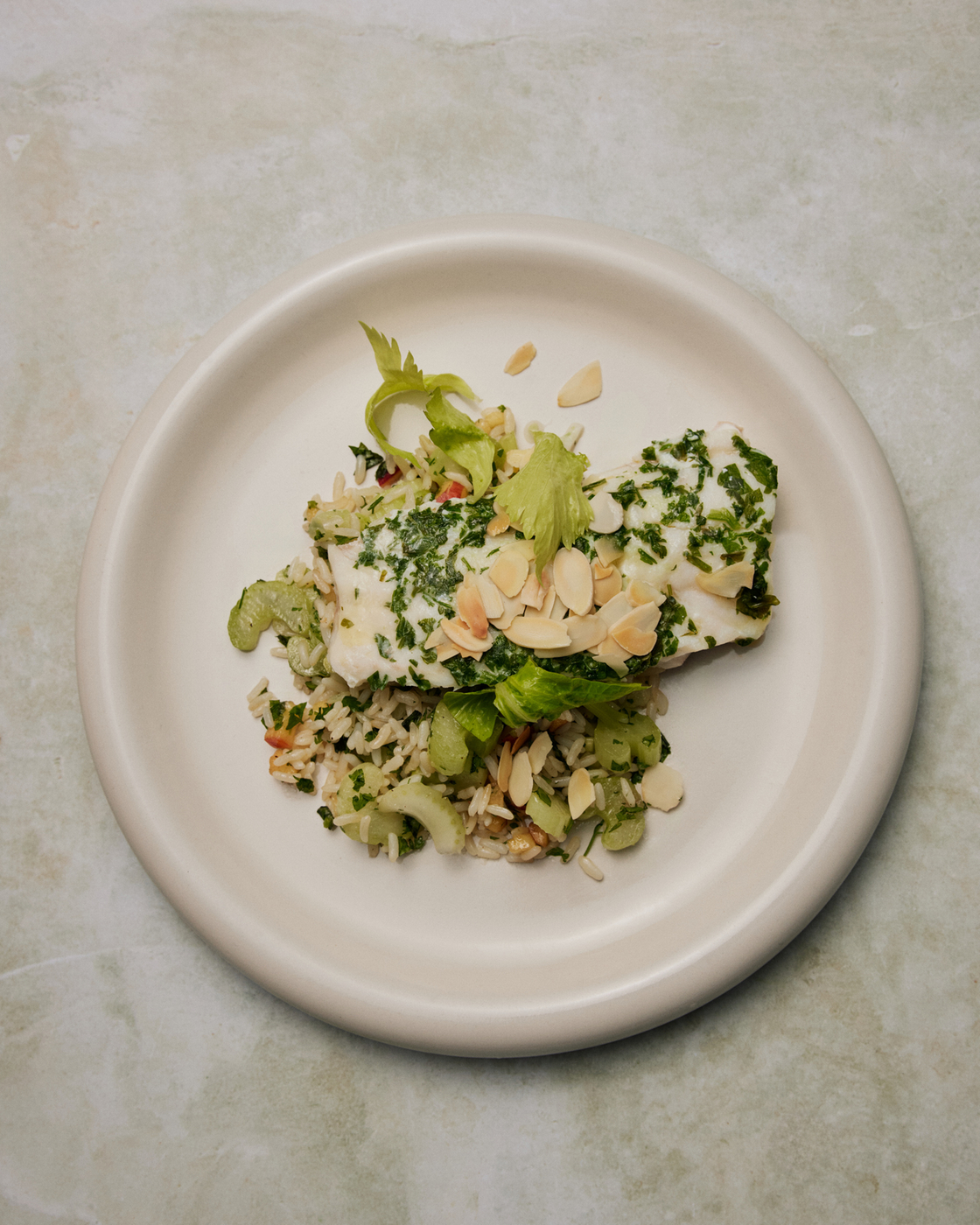 Fish dish with rice, herbs and slivered almonds on a plate, perfect for the kitchen or cooking inspiration.