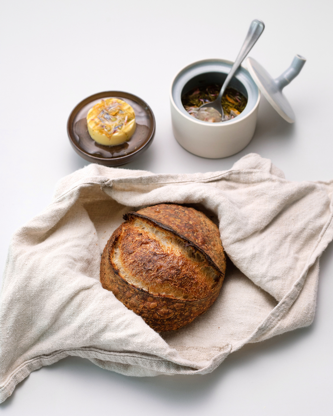 Freshly baked bread with butter and herb dip on a white background