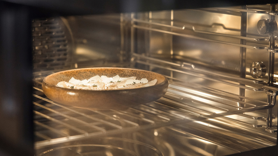 Modern oven with a pizza on a wooden board inside