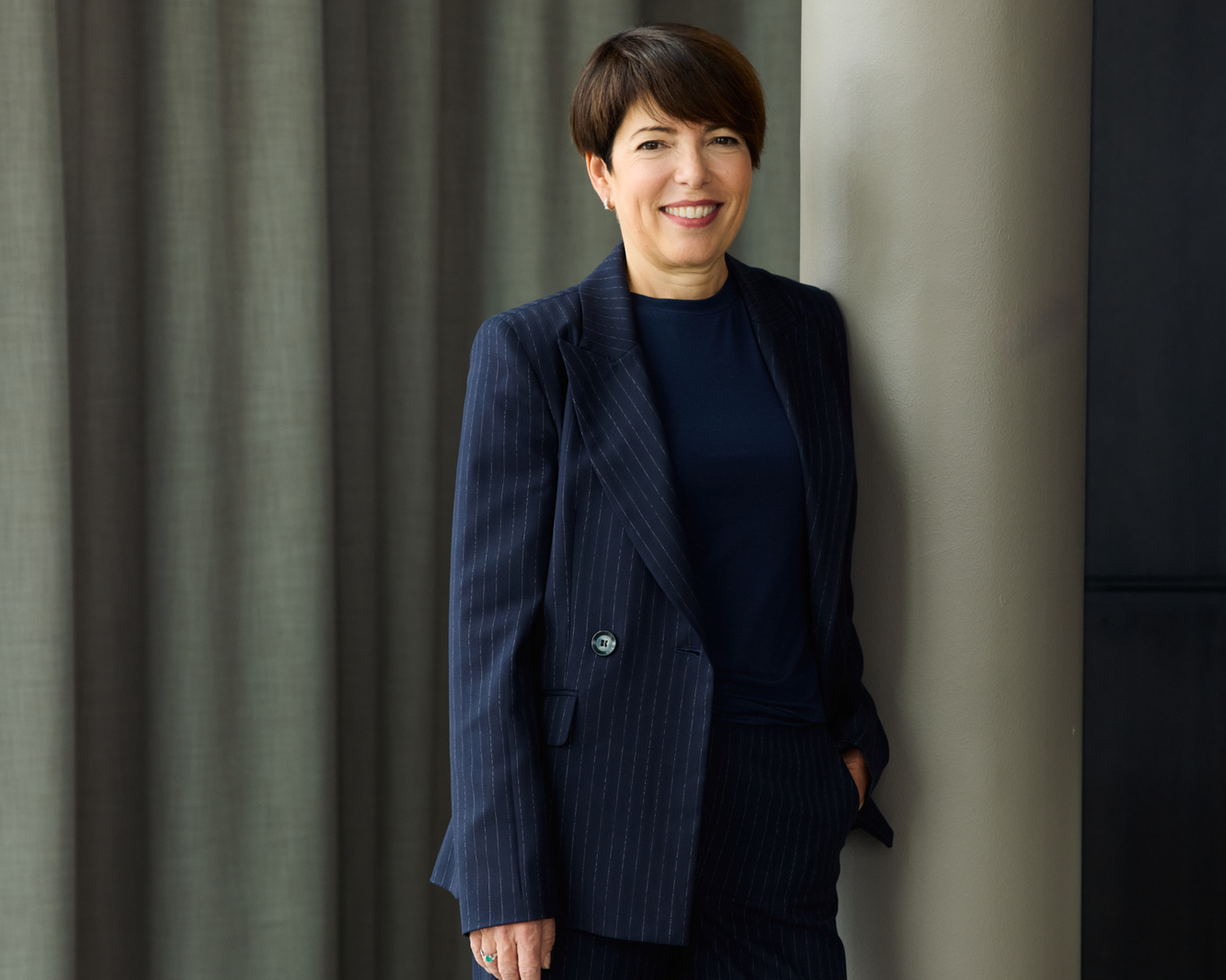 Person in an elegant dark blue suit in front of a stylish background