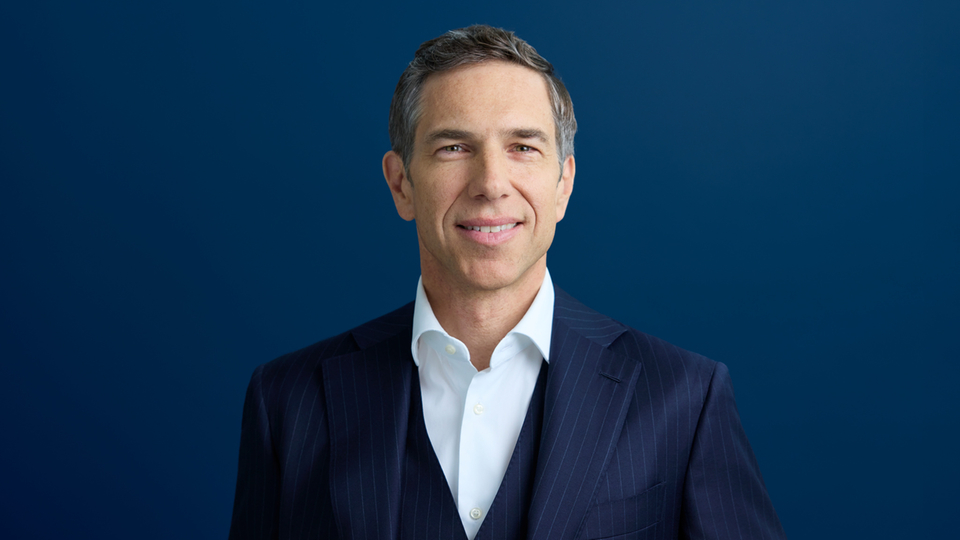 Portrait of a man in an elegant suit against a blue background.