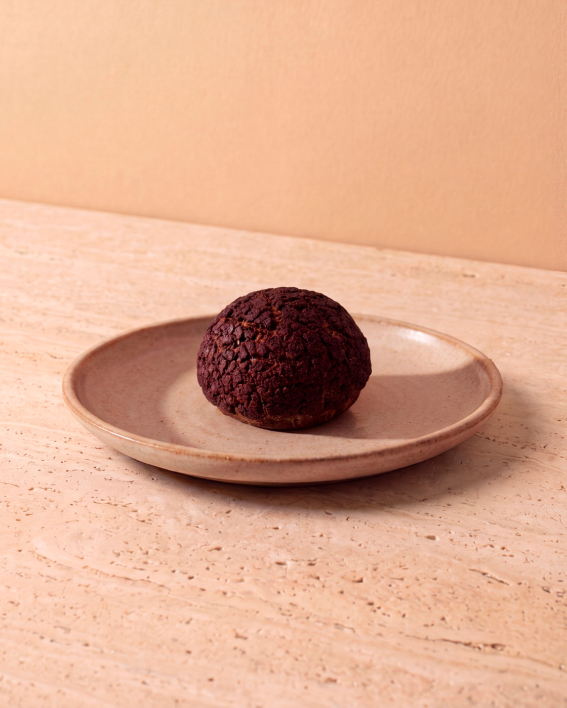 Dessertkugel auf einem schlichten Teller auf heller Steinoberfläche in minimalistischer Szene
