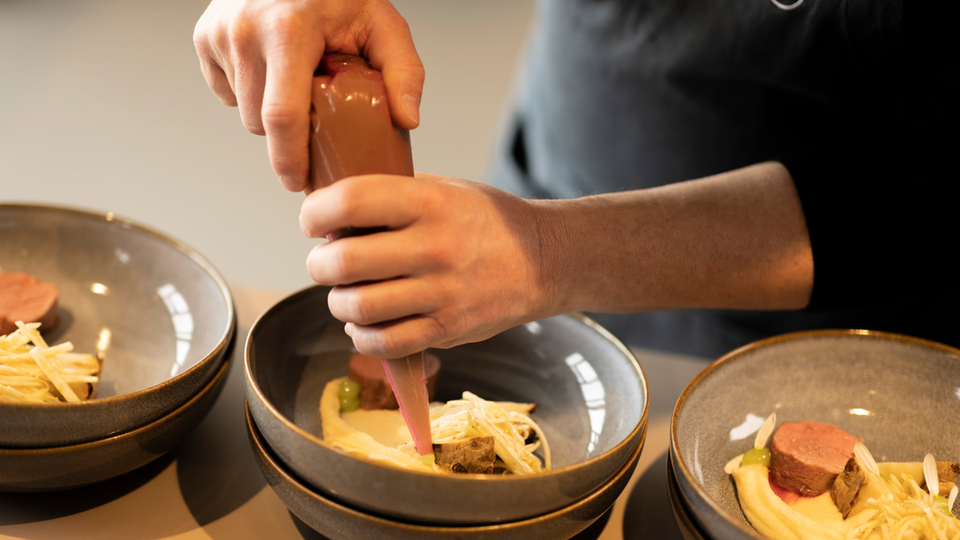 Presentazione di un piatto gourmet in ciotole con sac à poche e ingredienti disposti con cura