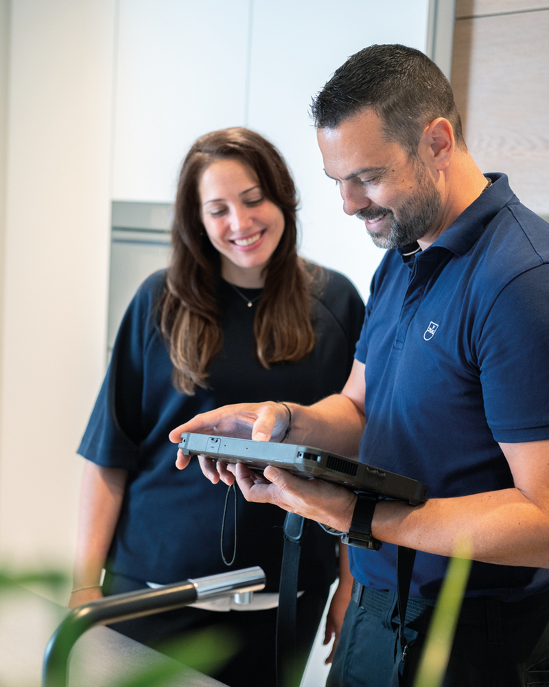 Tecnico dell'assistenza con una cliente in una cucina moderna mentre le fornisce consulenza su un elettrodomestico tramite un tablet