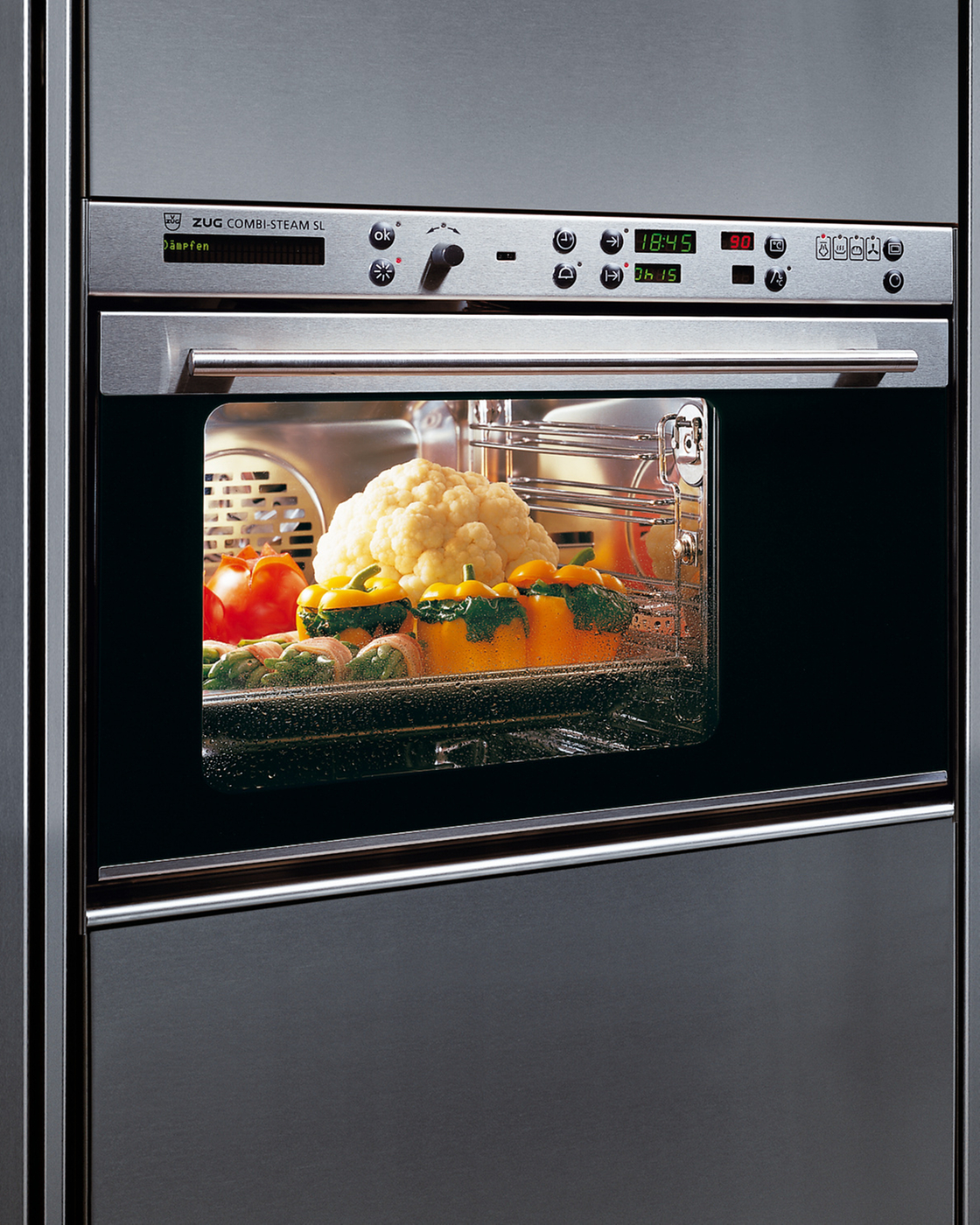 A steamer with vegetables in the cooking chamber of a modern built-in appliance