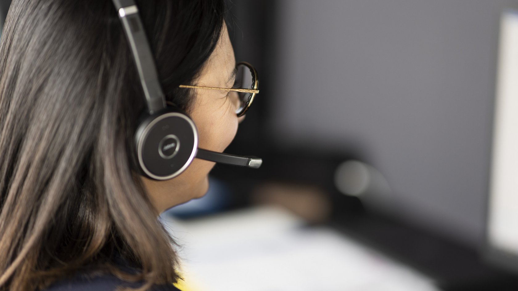 Support-Mitarbeiterin mit Headset bei der Arbeit am Computer