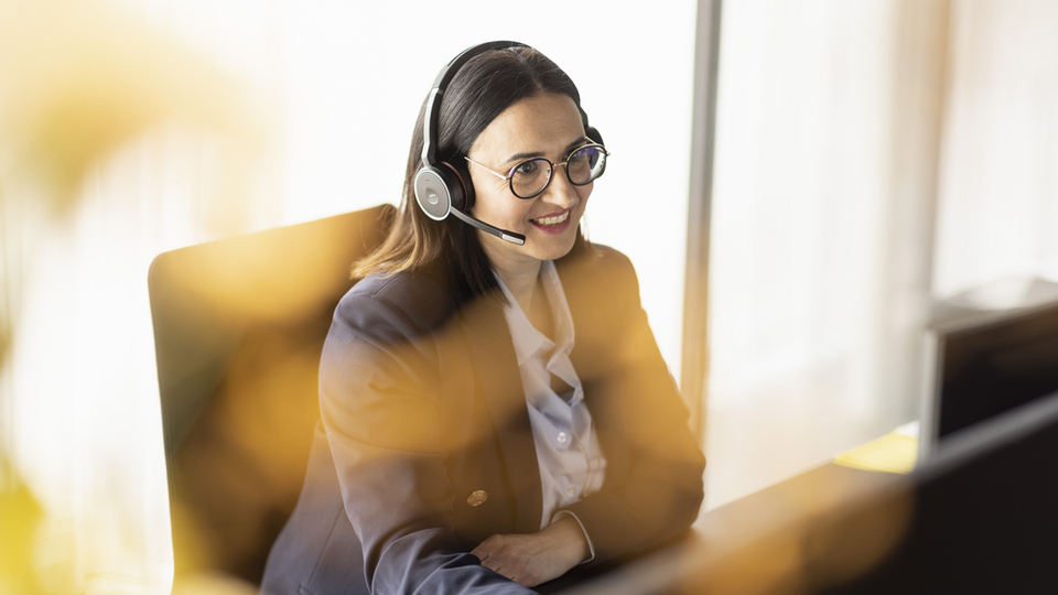 Support employee with headset at her desk in a modern office