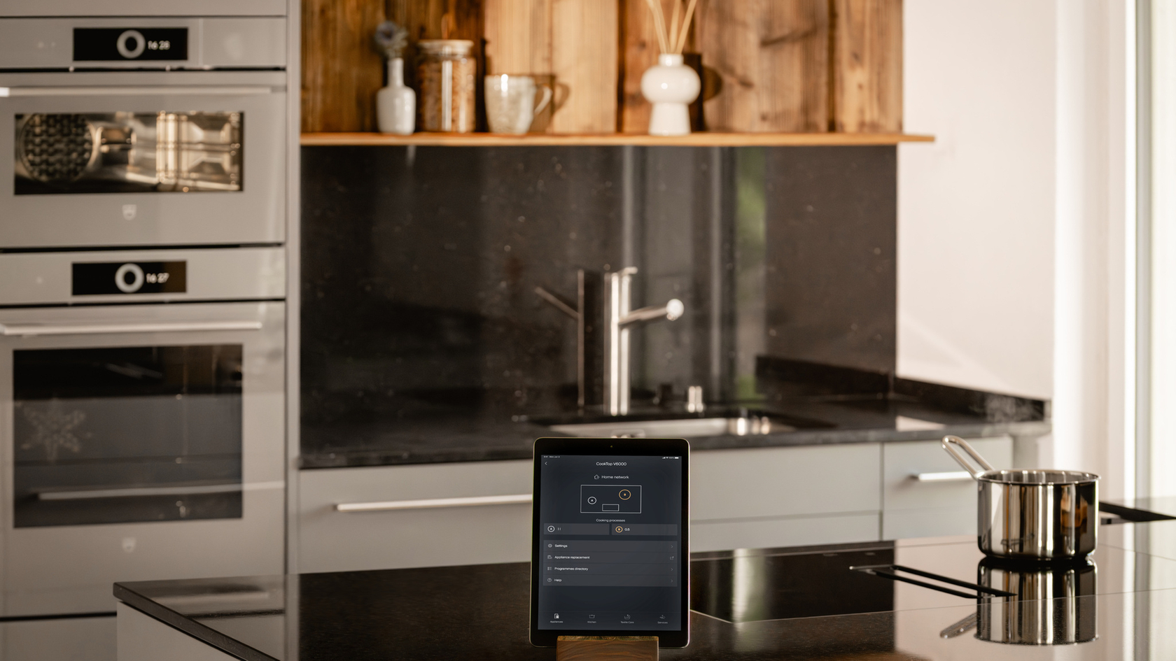 Moderne Küche mit Kochfeld, Tablet und hochwertigen Töpfen in stilvollem Design