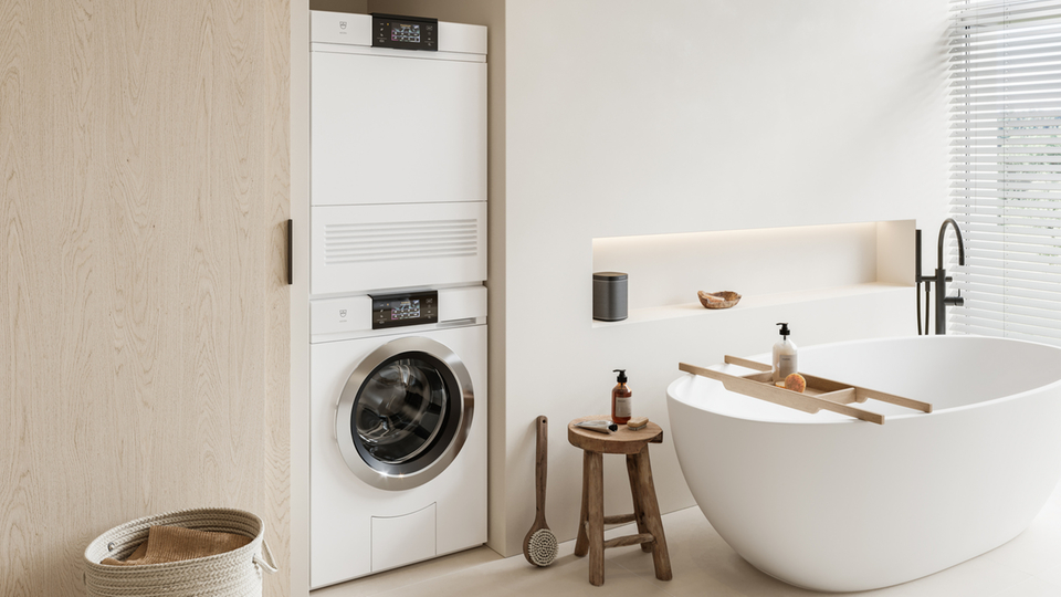 Modernes Badezimmer mit integrierter Waschmaschine und Wäschetrockner neben einer freistehenden Badewanne