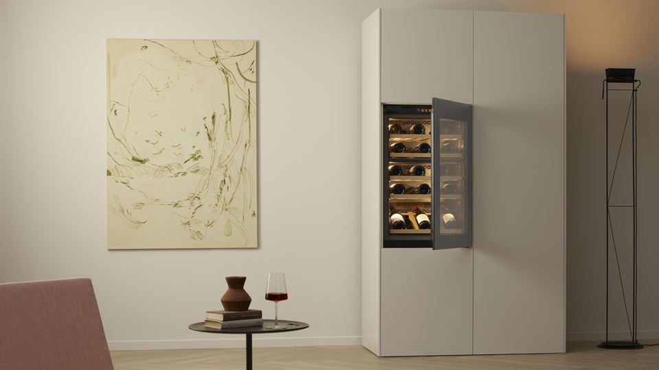 Weinschrank mit geöffneter Tür in einem modernen Wohnzimmer mit Kunstwerk und minimalistischem Design.