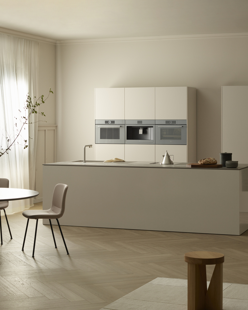Moderne Küche mit eingebauten Backöfen, Steamer und Kaffeemaschine in einem minimalistischen Design.