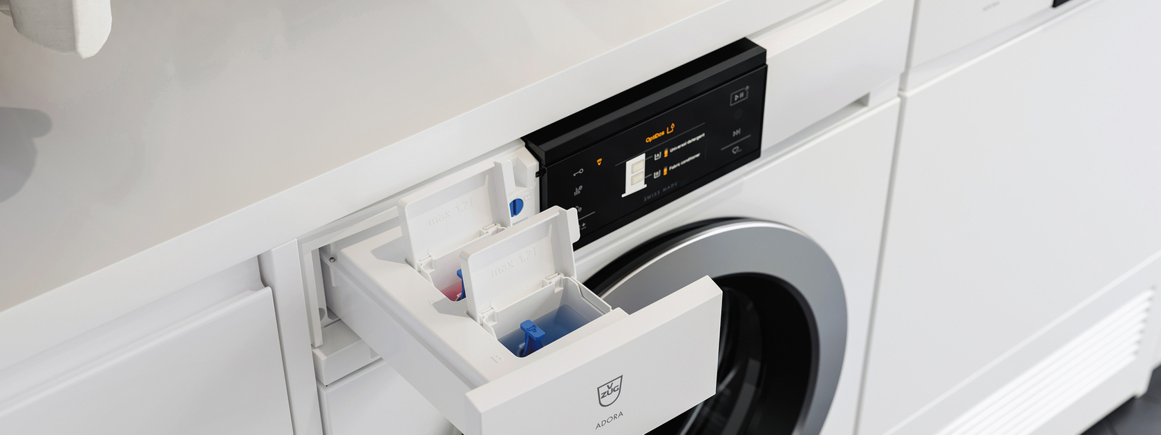 Washing machine with detergent compartment open and laundry folded on the work surface.